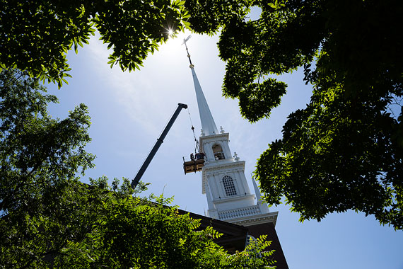 Workers carefully install the new bell. 