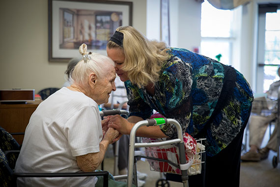 Nurse kissing older woman on head