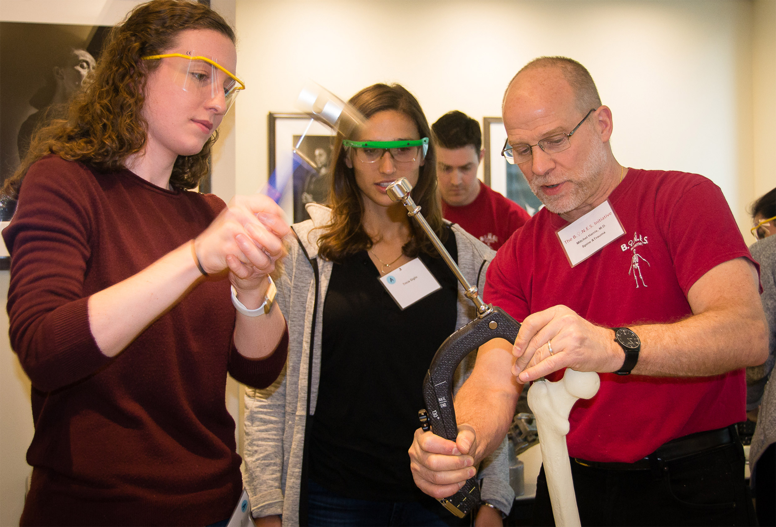 Mitchel Harris demonstrates to Heleyn Grissom (left) and Tricia Giglio methods to place an intramedullary nail on a femur sawbones model.