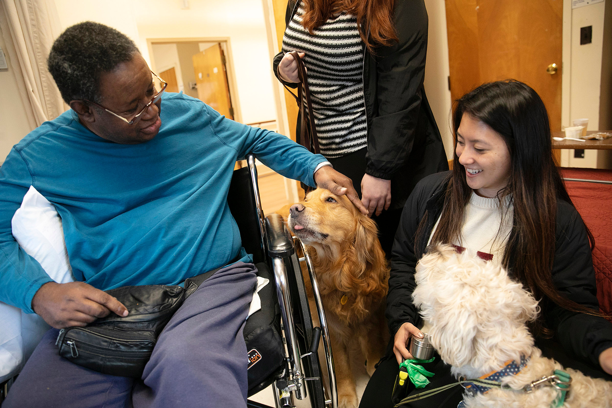 Man petting dog, woman kneely with dog