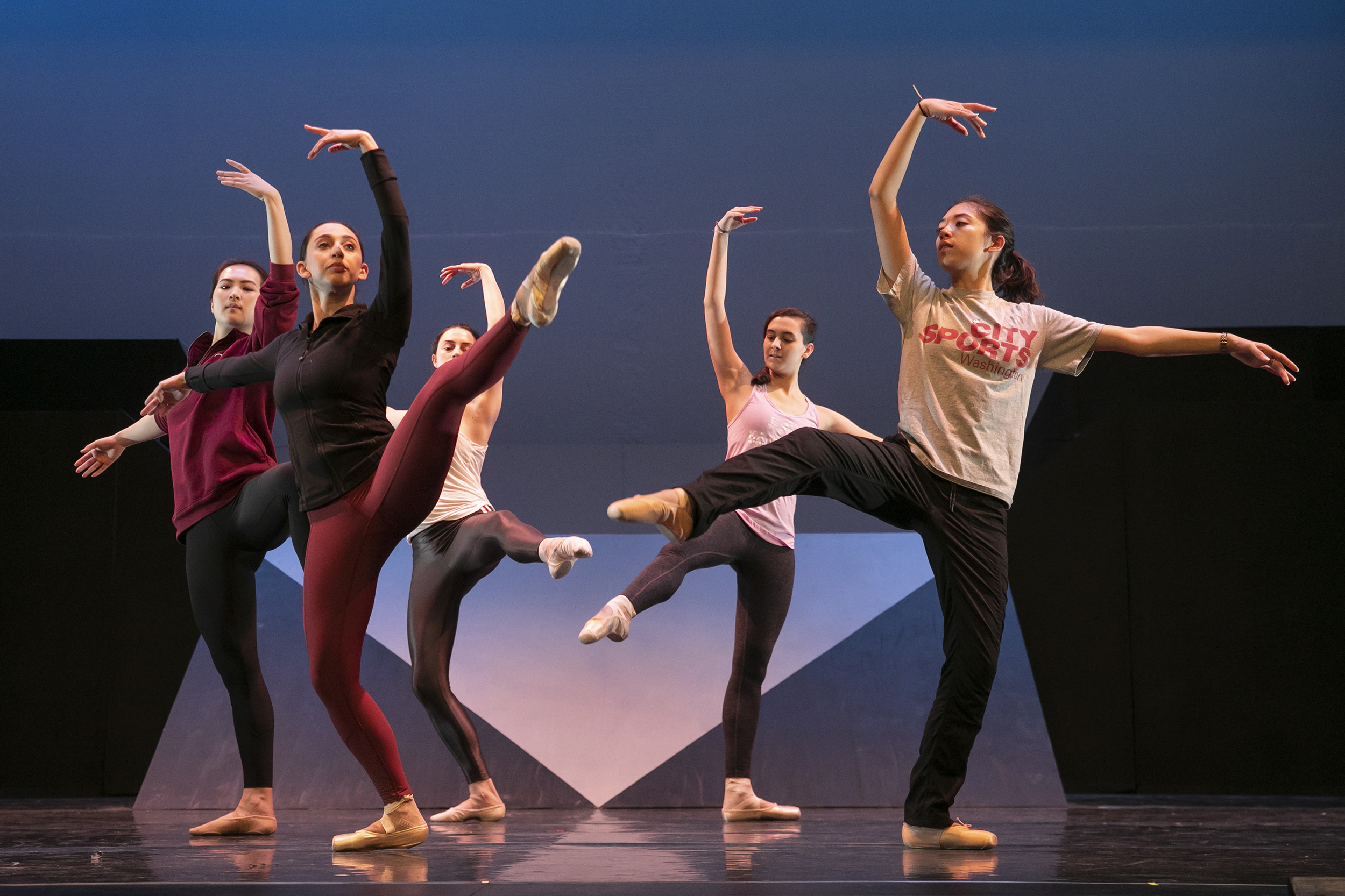 Five dancers pose with arms and legs outstretched.