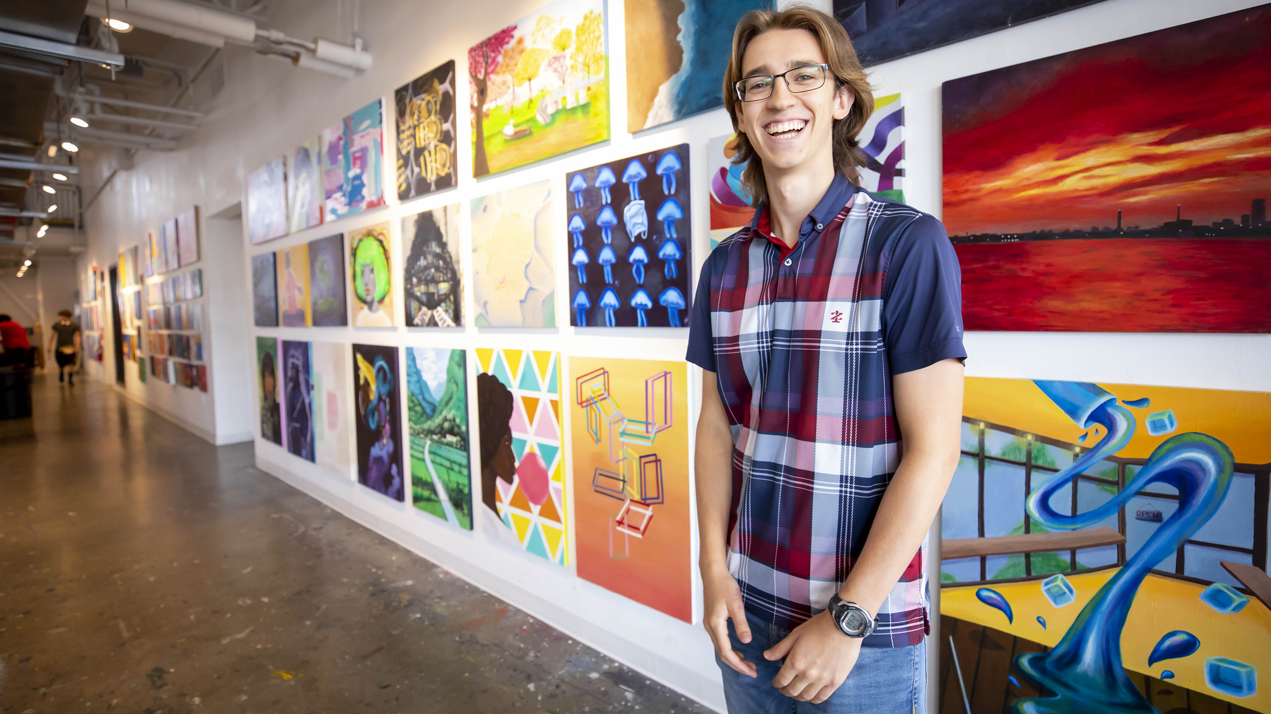 Harvard first year student standing in front of student artwork on wall.