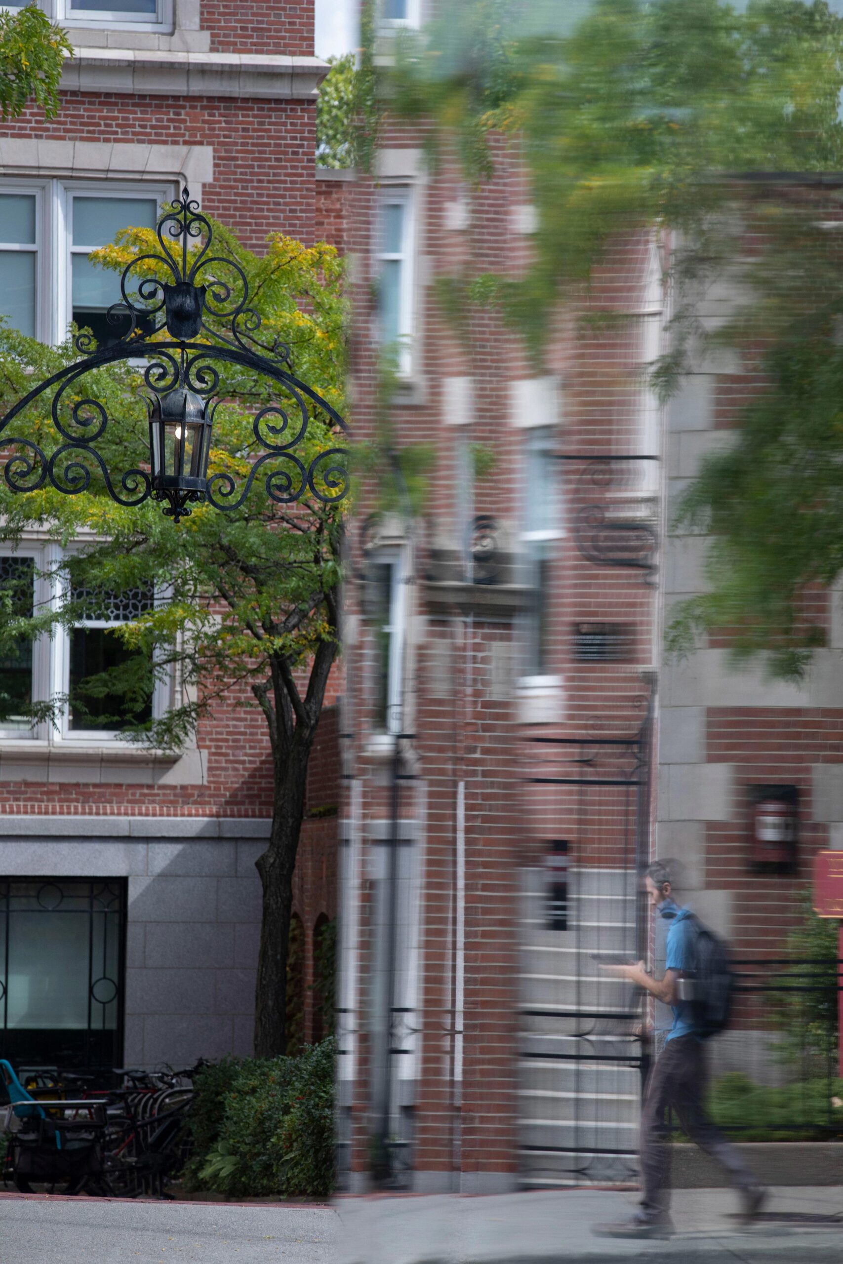 A student passes by a brick building, vertical picture.