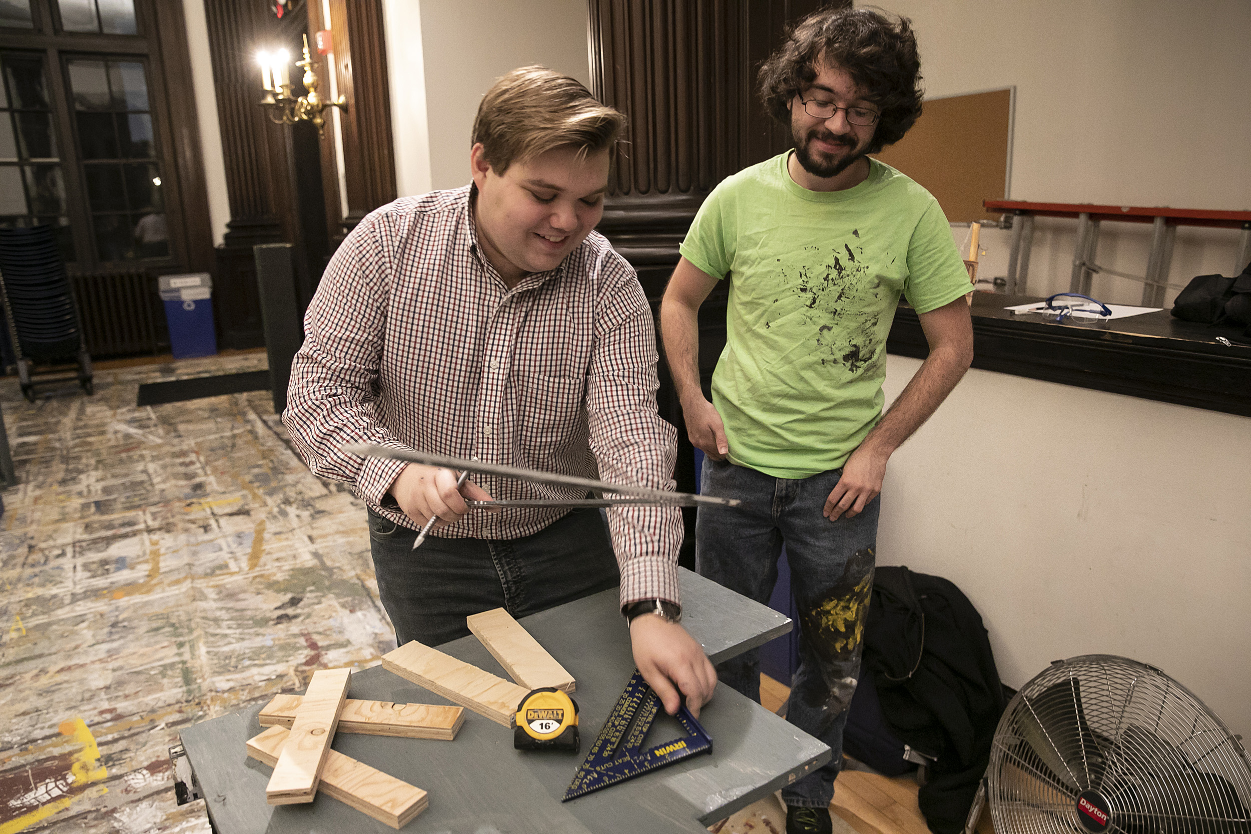 Two students work on a wooden set piece