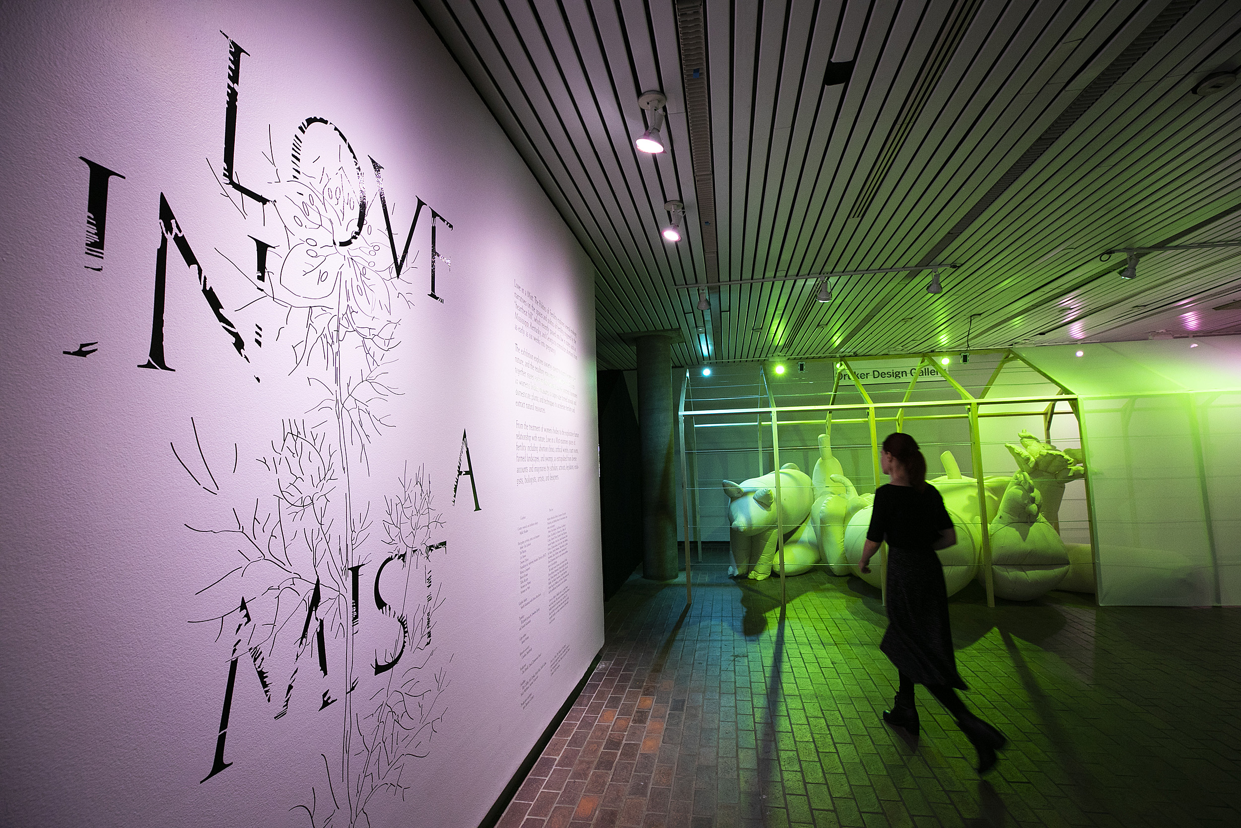 Passerby bathed in neon walks through the exhibition space.