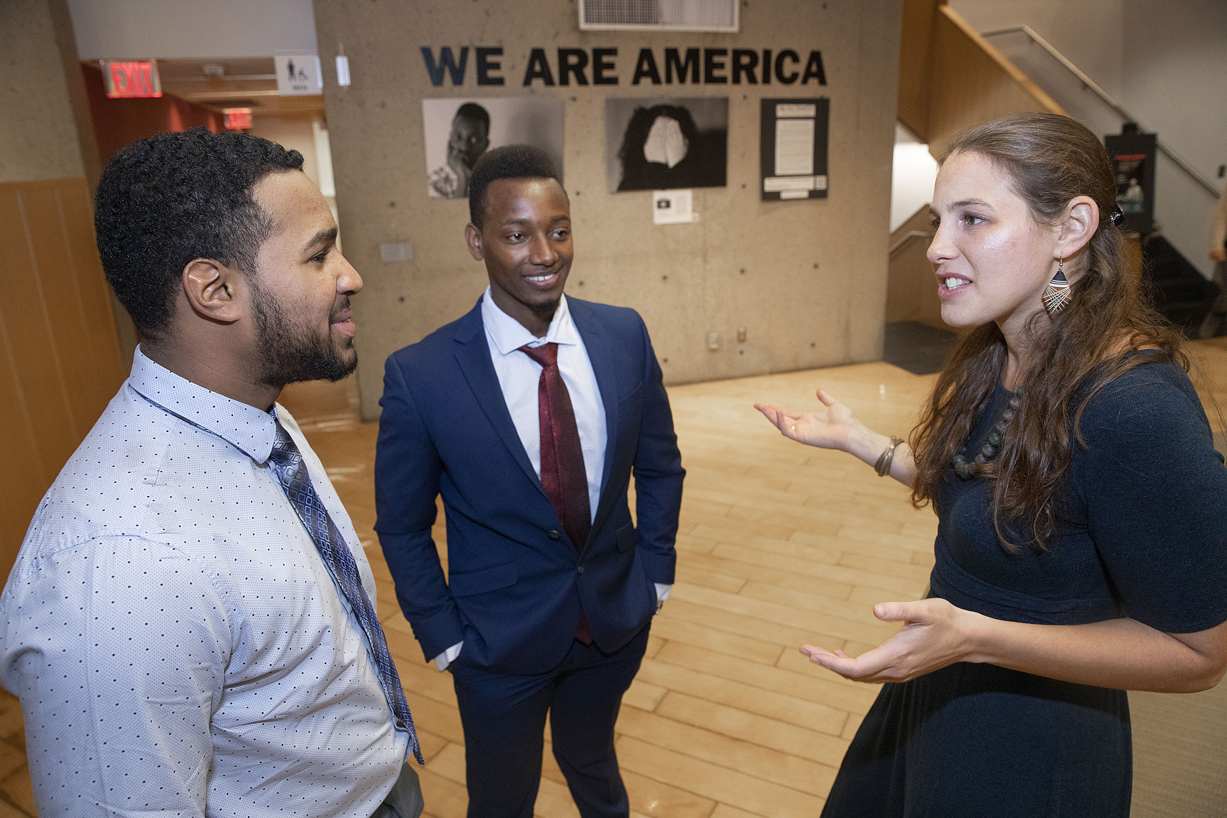 Teacher Jessica Lander with students Ezequiel Nunez and Robert Aliganyira in the 'We Are America' photo exhibit at Gutman Library.