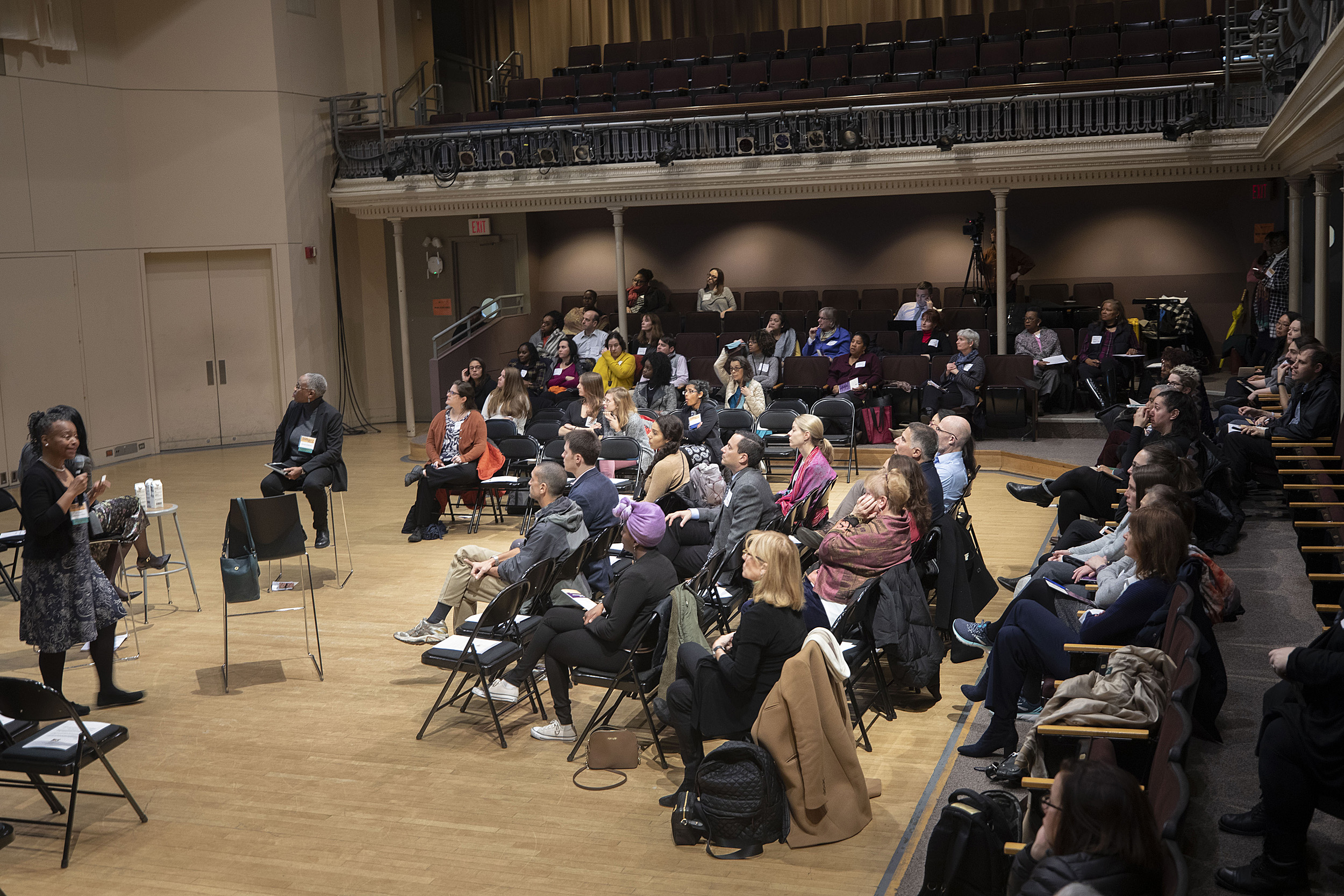 Audience in folding chairs listening to panelists.