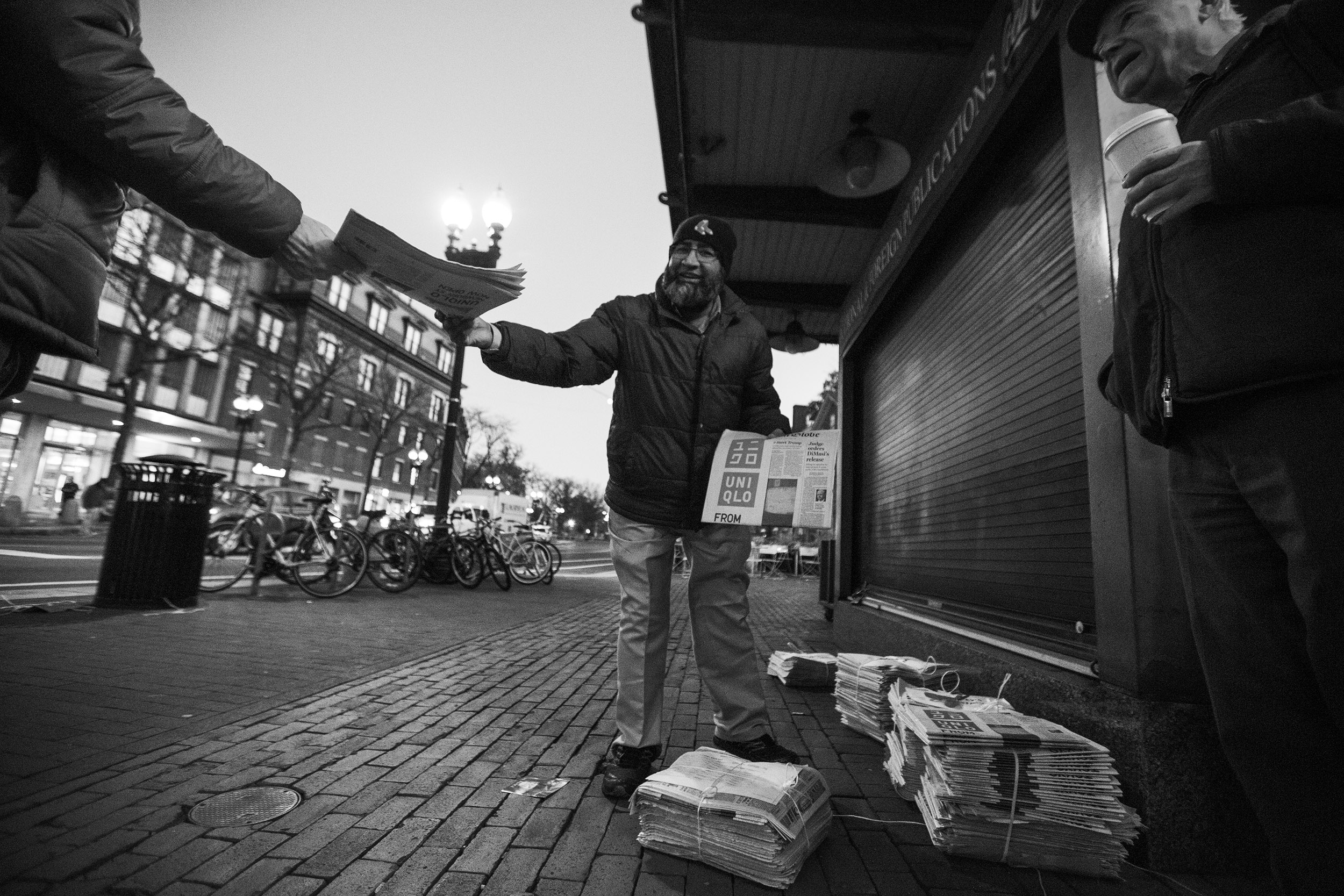 Mohamed Rahman hands out newspapers in Harvard Square.