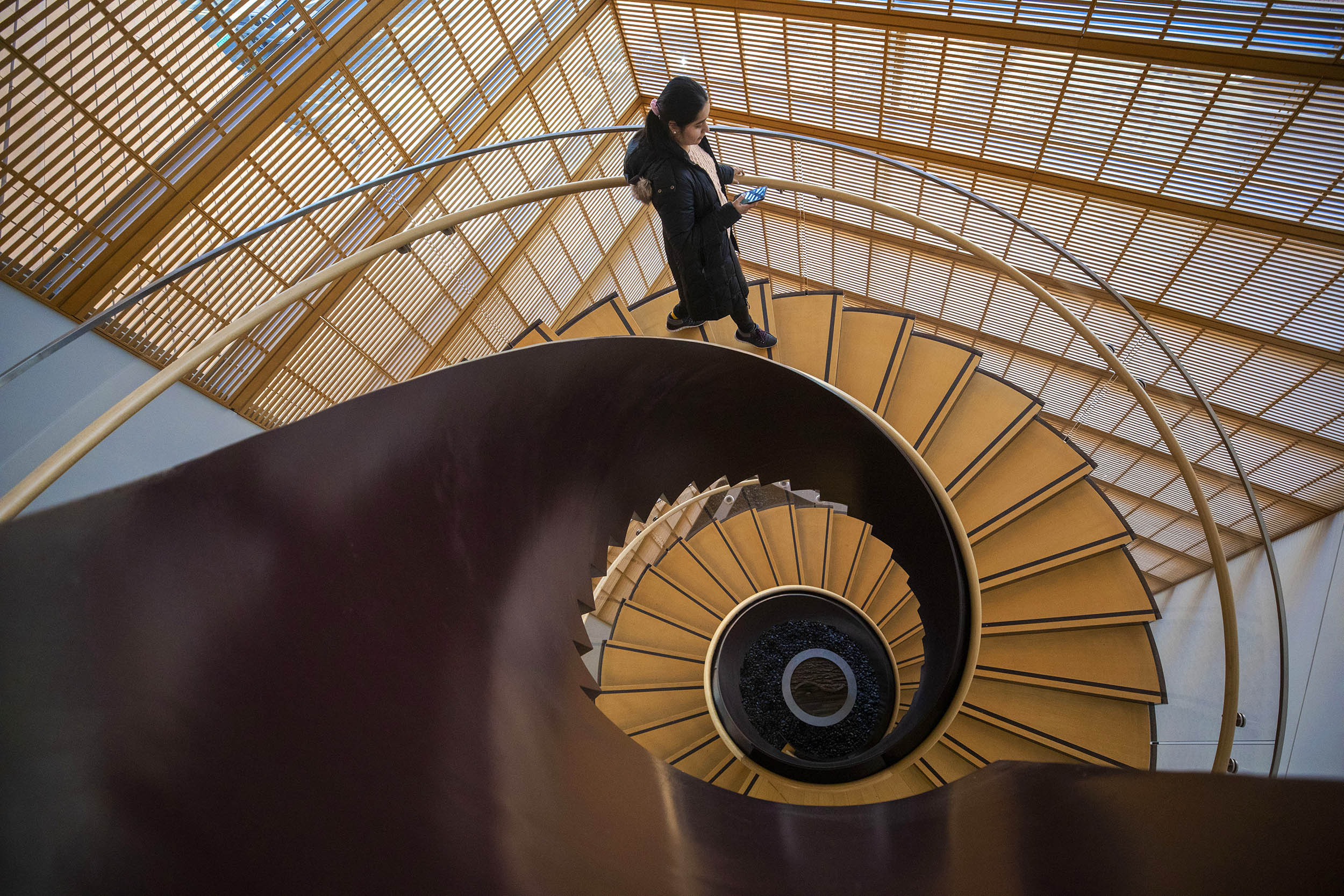 Shubhangi Bhadada appears at the crest of a wave-like spiral staircase at the Center for Government and International Studies.