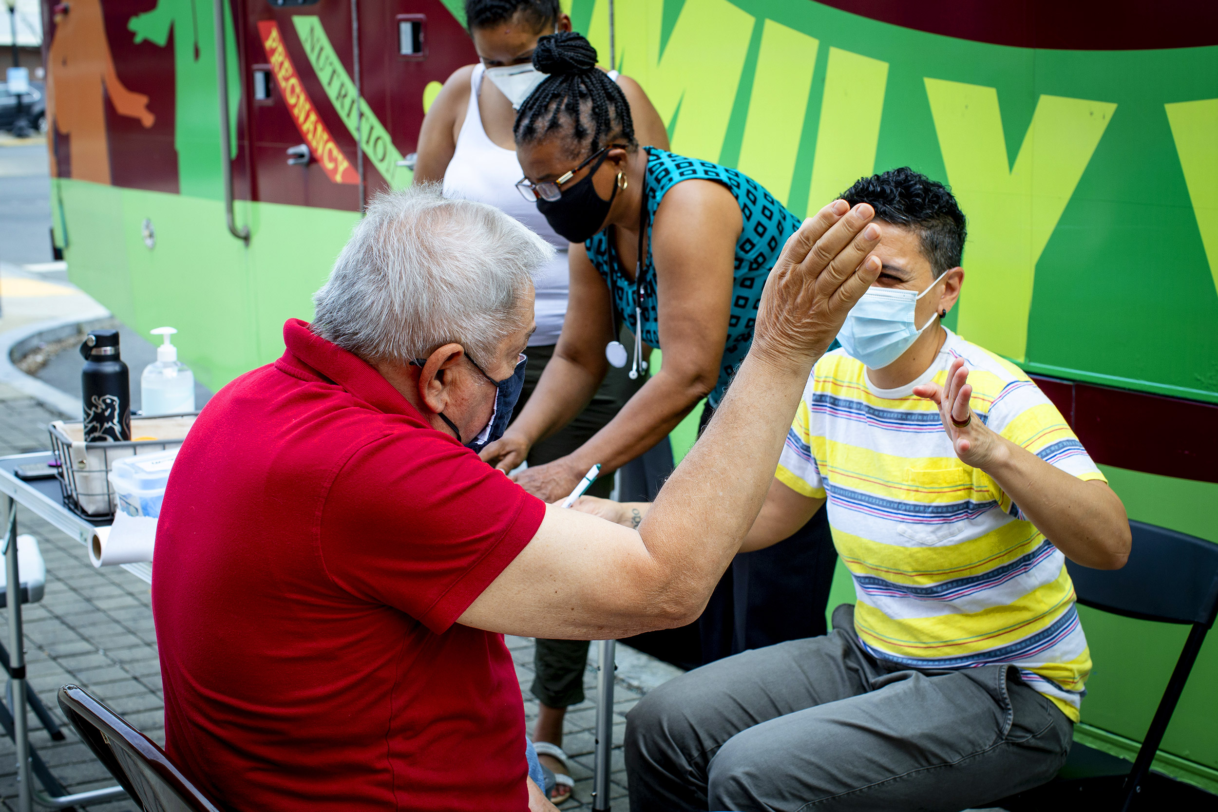 Simone de Oliveira, right, high fives a regular client, Joseph Rocca, of Winthrop, after administering his blood pressure test.