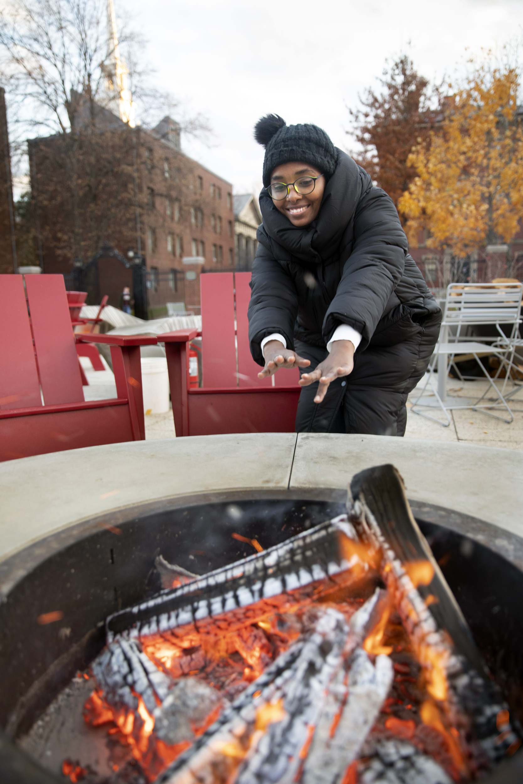 Alaa Hamid, a Graduate School of Design student, warms hands by a fire pit.