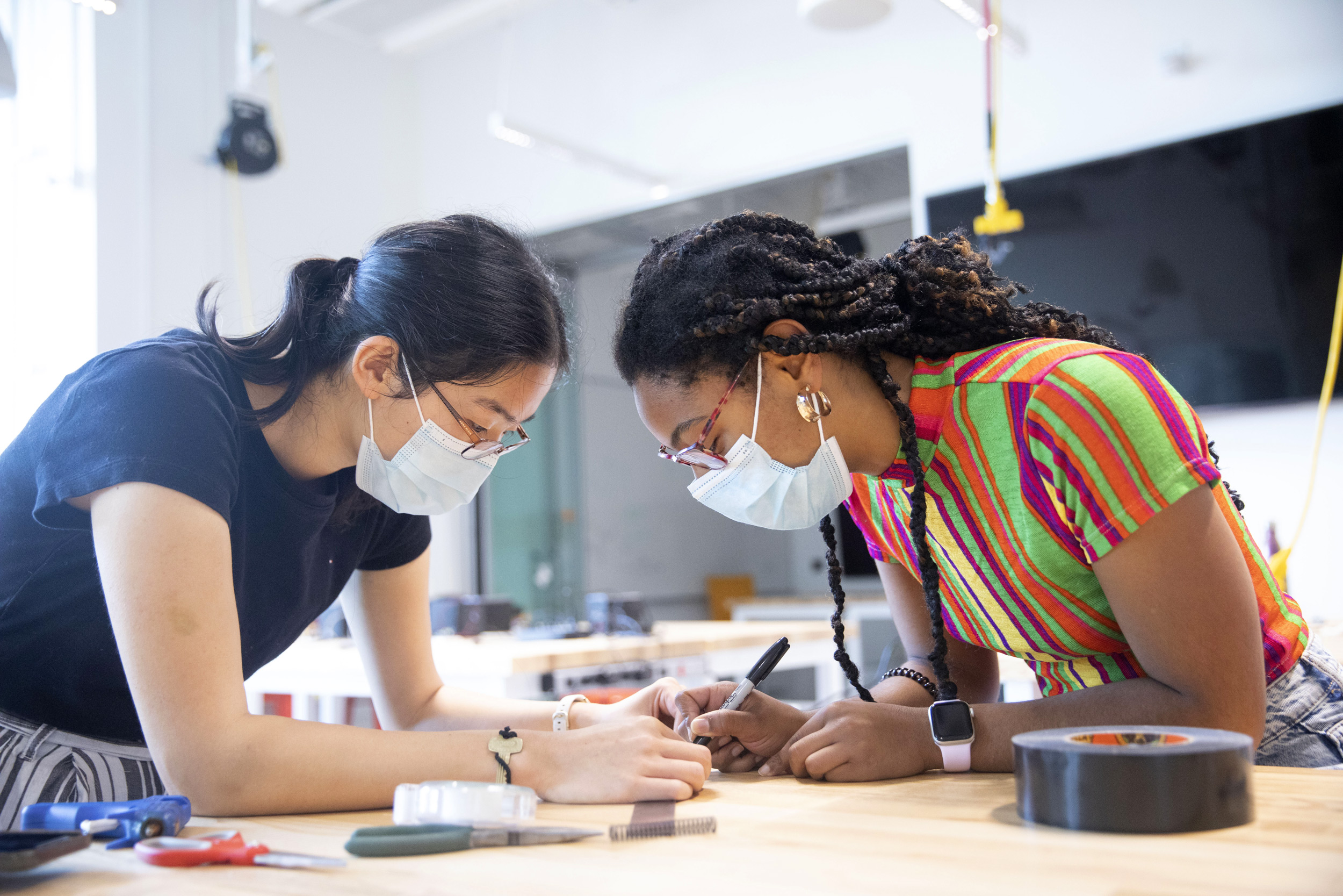 Sophia Lang ’23 (left) and Ayana Gray ’23 make a miniature pool table, complete with a spring-loaded cue stick for a project in Applied Physics 50.