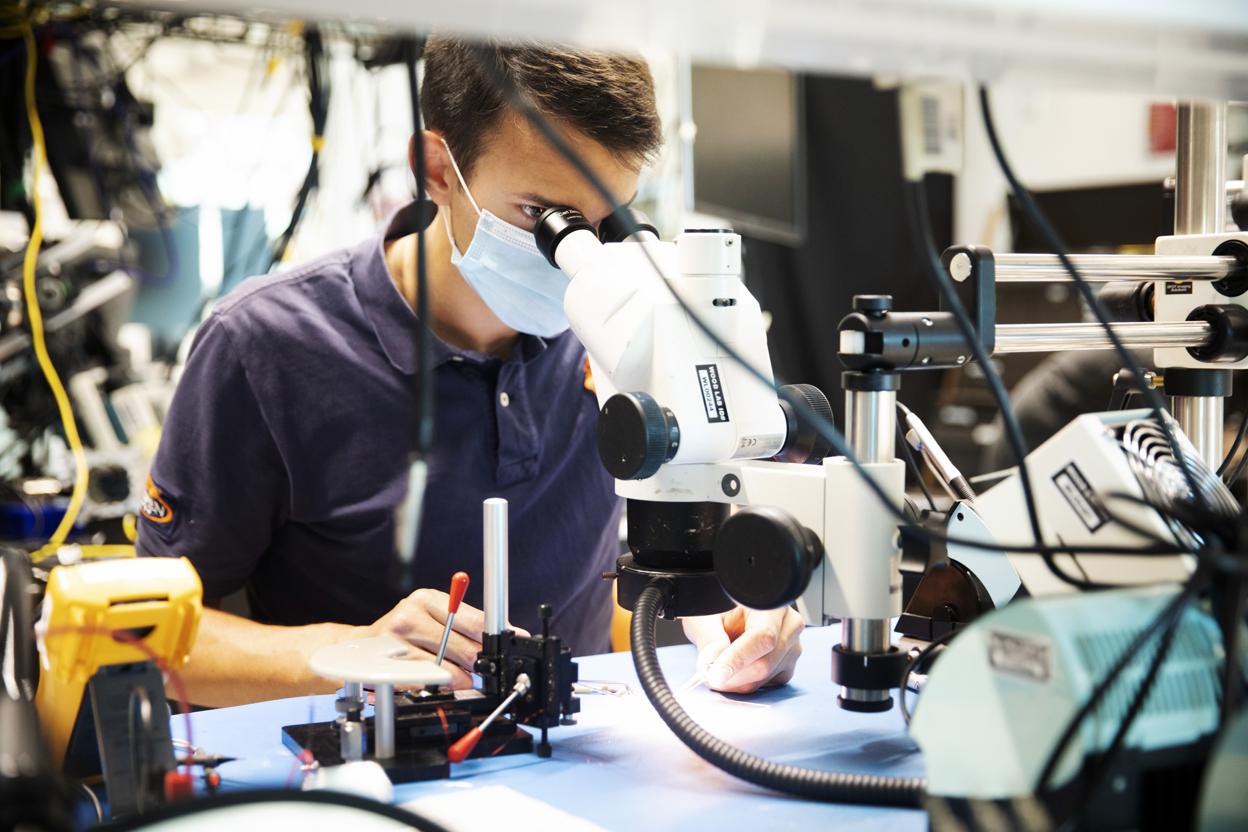 Pierre-Louis Lechère assembles a HAMR under a microscope as in the Microrobotics Laboratory.