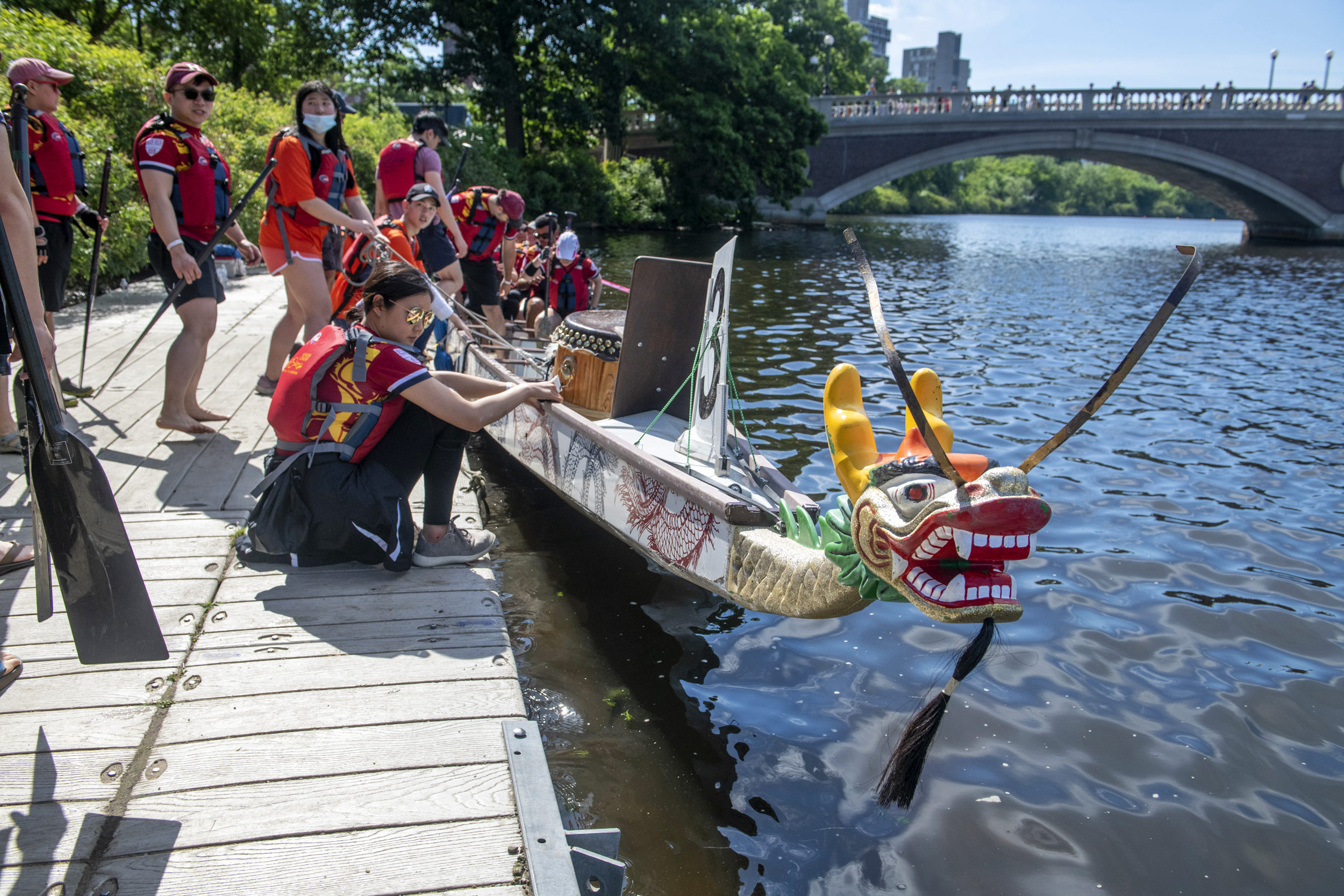 Crew members board a vessel from the Weeks Footbridge dock to start the Boston Dragon Boat Festival.