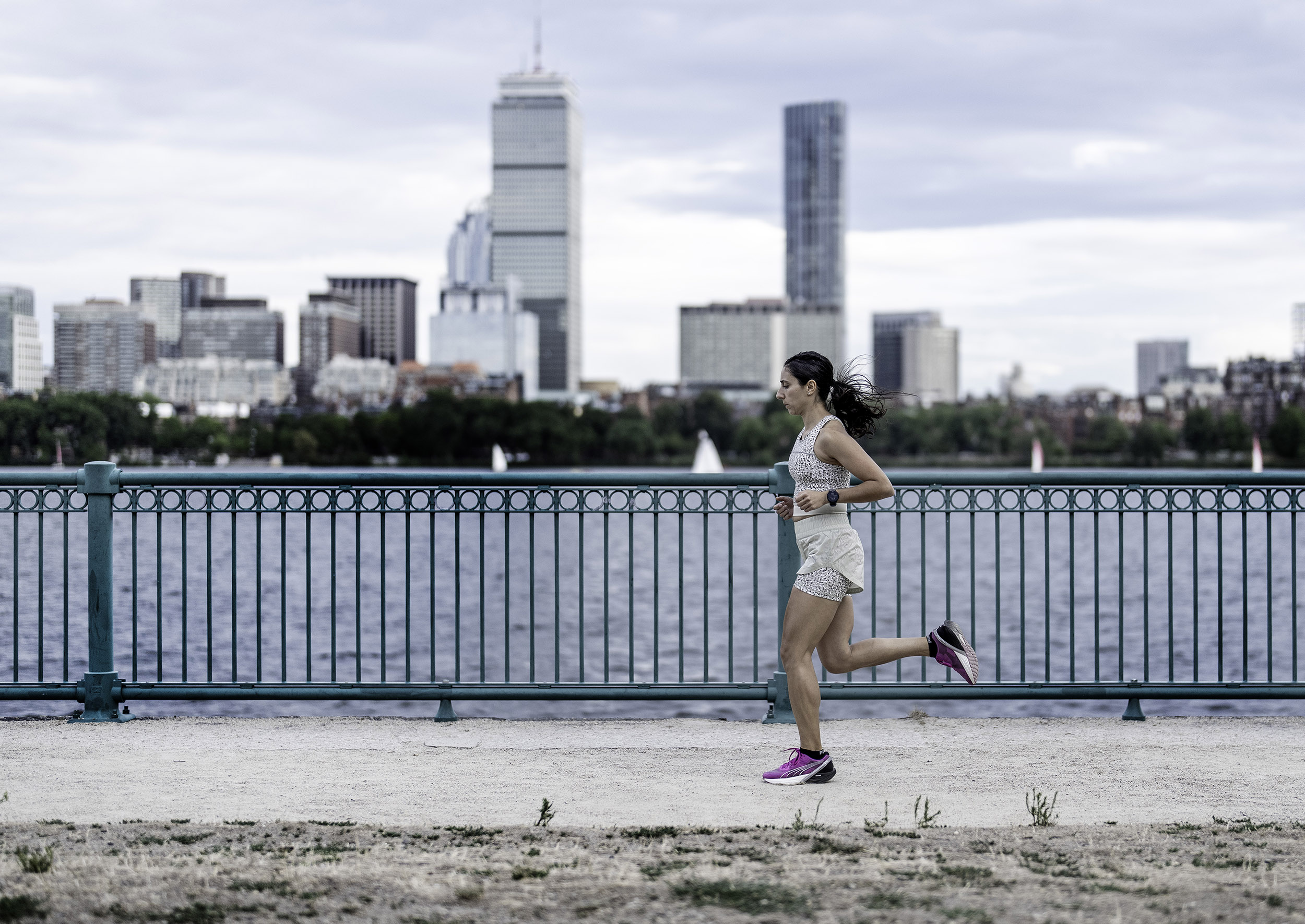 Alia Qatarneh runs along Charles River with Boston skyline in background.