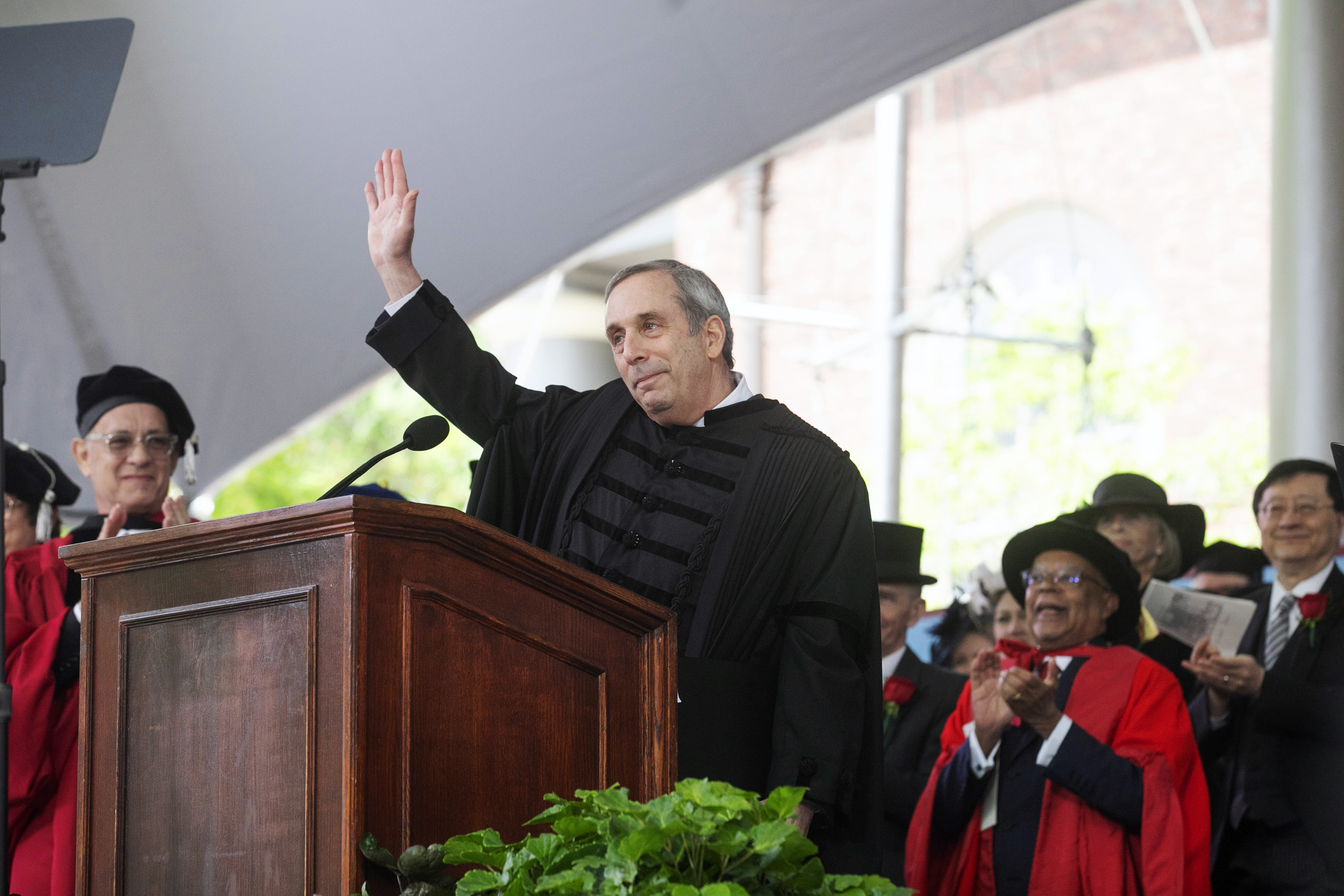 Larry Bacow waves at podium.