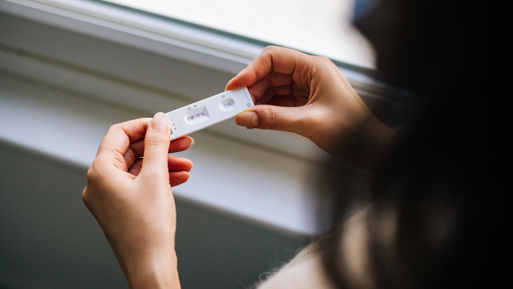 Woman Holding a Covid-19 Rapid Test At Home.