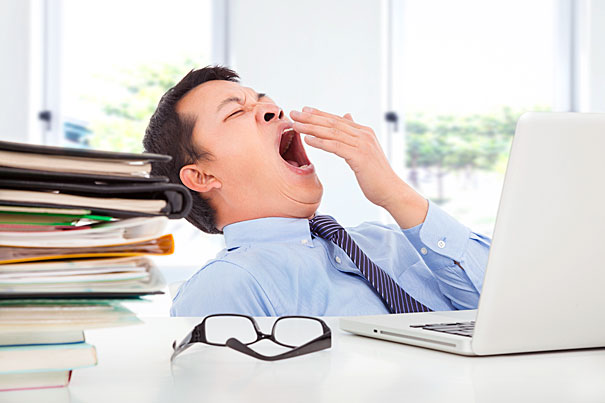 Exhausted young businessman yawning at work in office