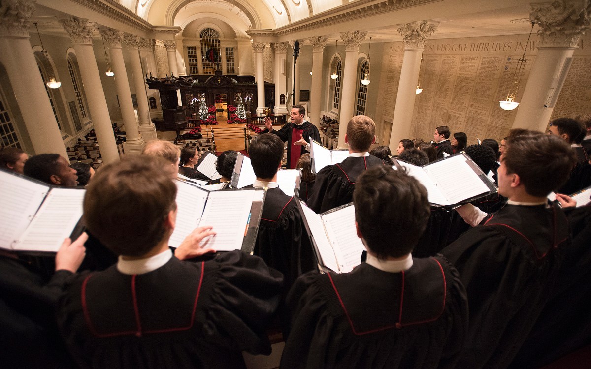 Choirmaster conducts Harvard choir during Christmas service in Memorial Church.