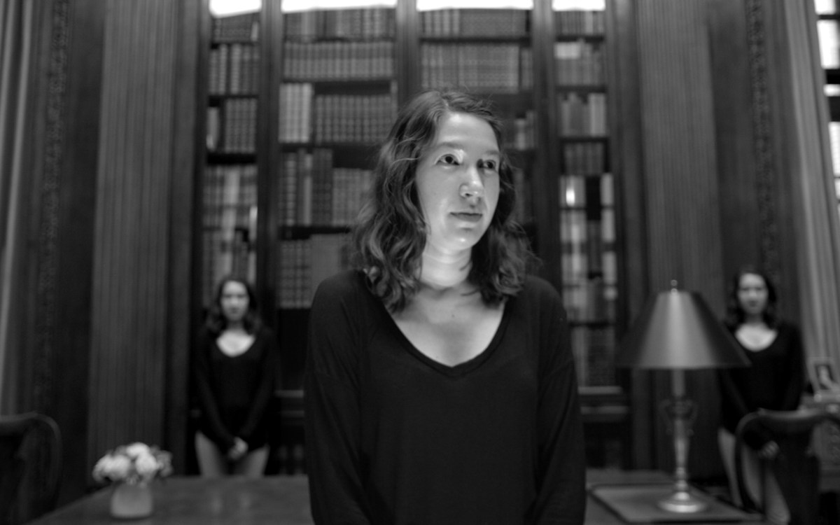 Young woman in the foreground of a black and white image; shadowy people in the background