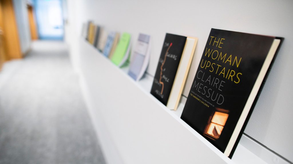 A row of books lines a shelf in the Department of English's creative writing program in Lamont Library.