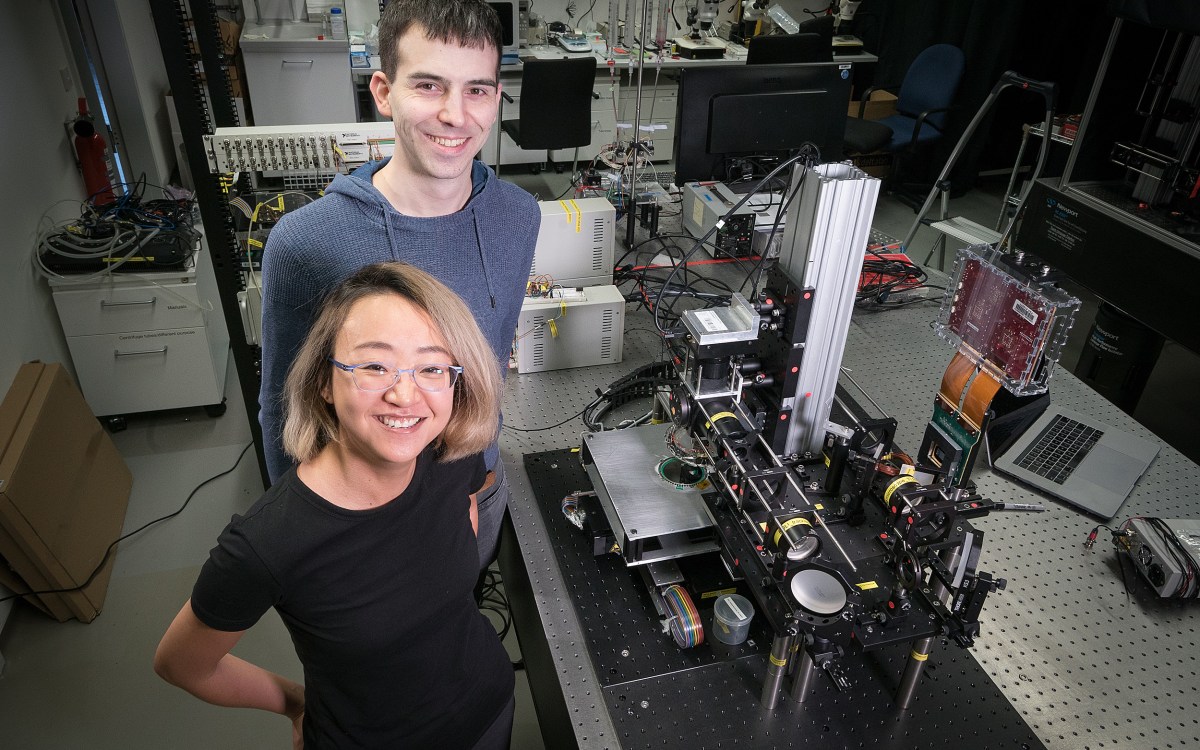 Two researchers in a lab with a large microscope.