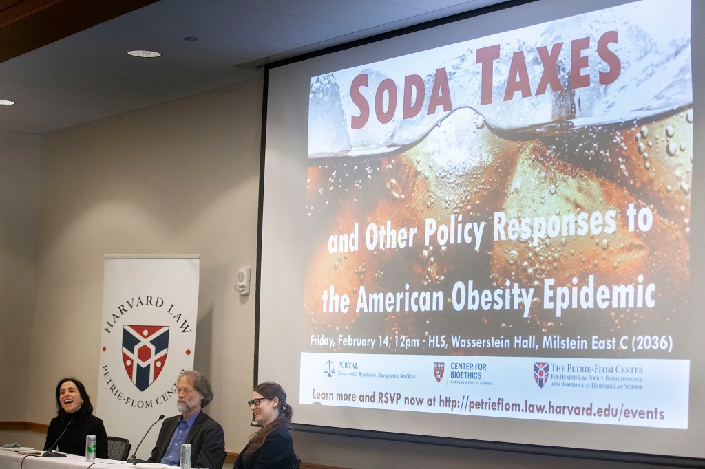 Three people sitting in front of a screen with Soda Taxes on it.