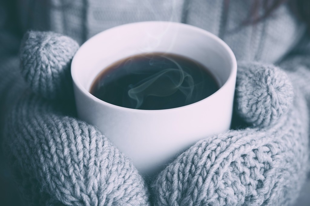 Mittens holding mug.