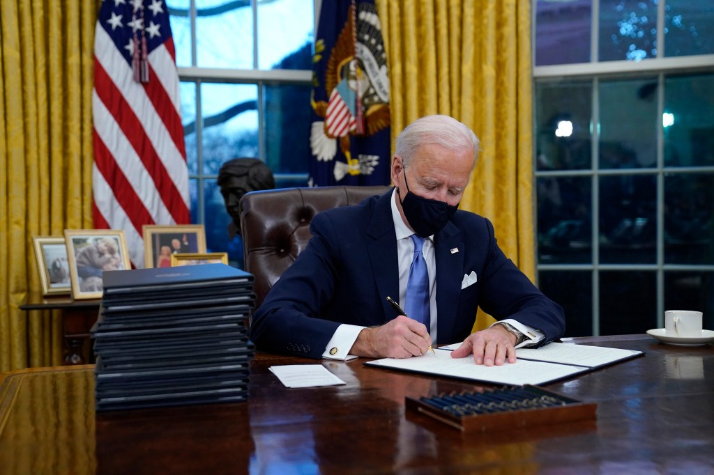 Joe Biden signs his first executive orders in the Oval Office.