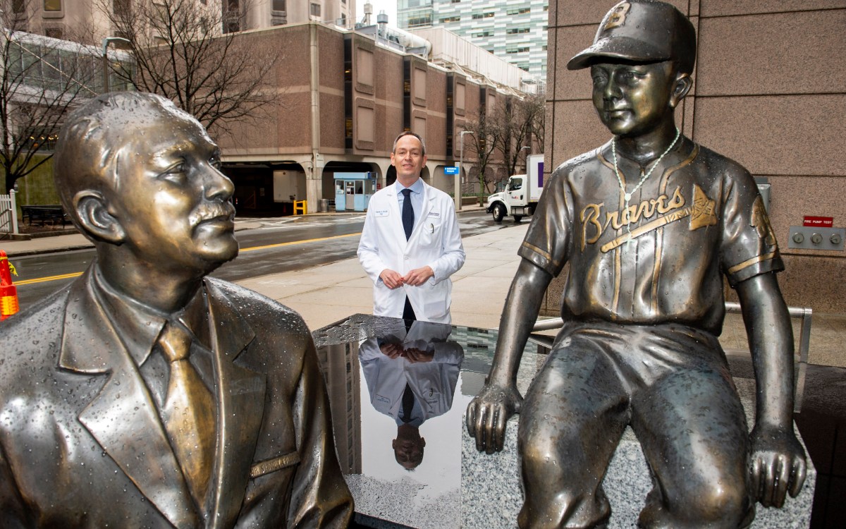 Patrick Ott, Associate Prof of Medicine at HMS and DFCI, stands by the statues of Dana-Farber founder Sidney Farber.