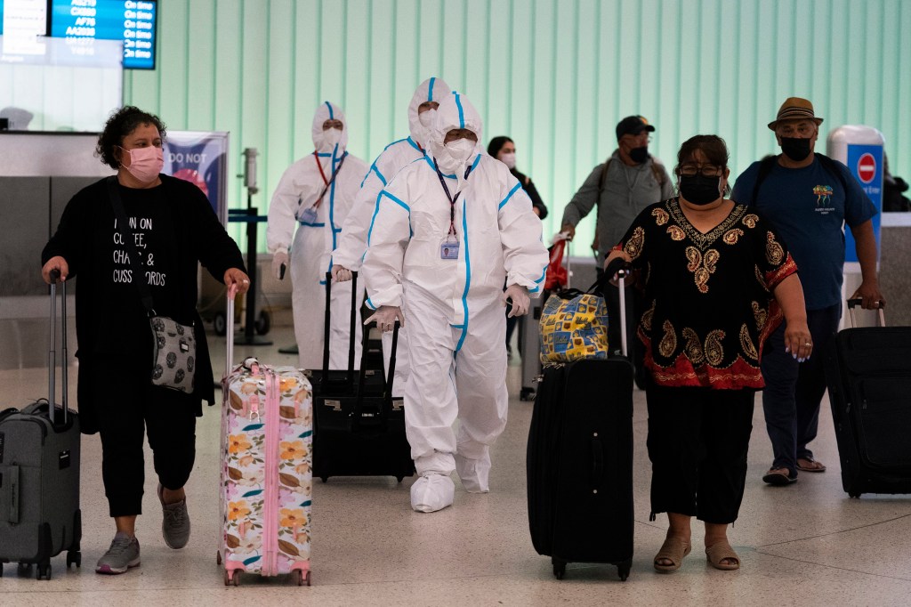 Flight crew members in hazmat suits walk through LAX.