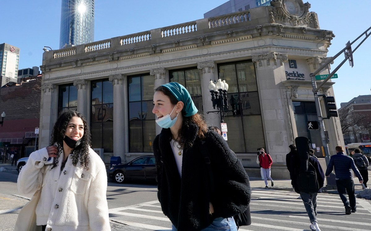 Pedestrians in Boston chat as they cross street with masks lowered.