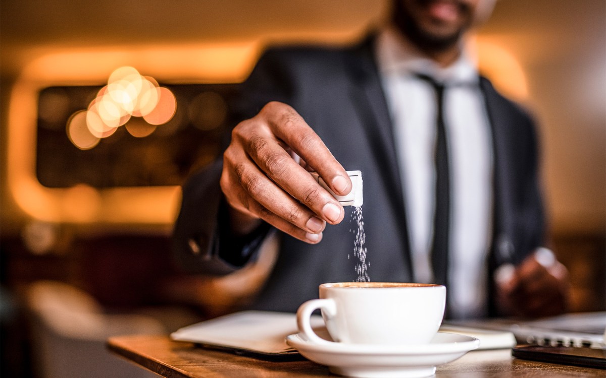 Man putting sugar in his coffee.