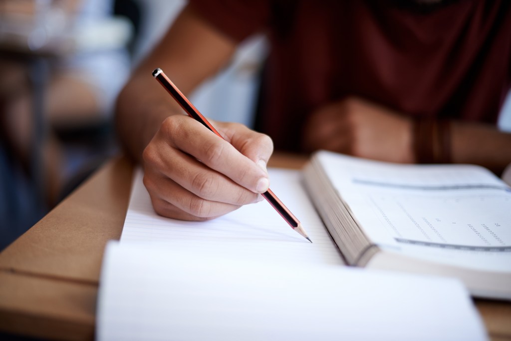 Student takes notes with textbook open.