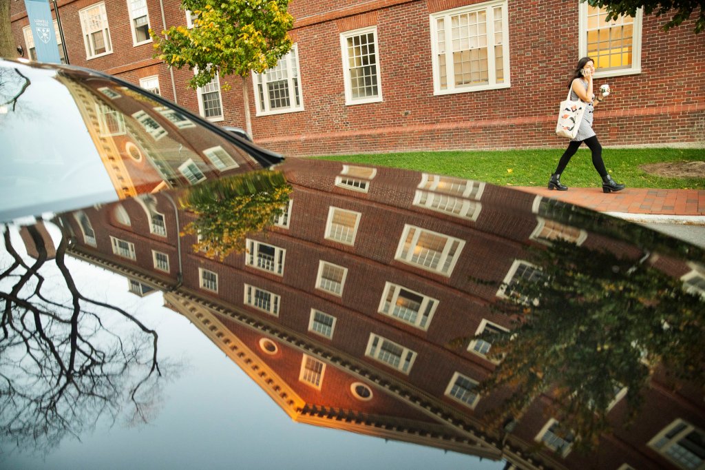 Lowell House is reflected in the surface of a car.