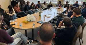 Harvard students and Michigan community members sit around a table.