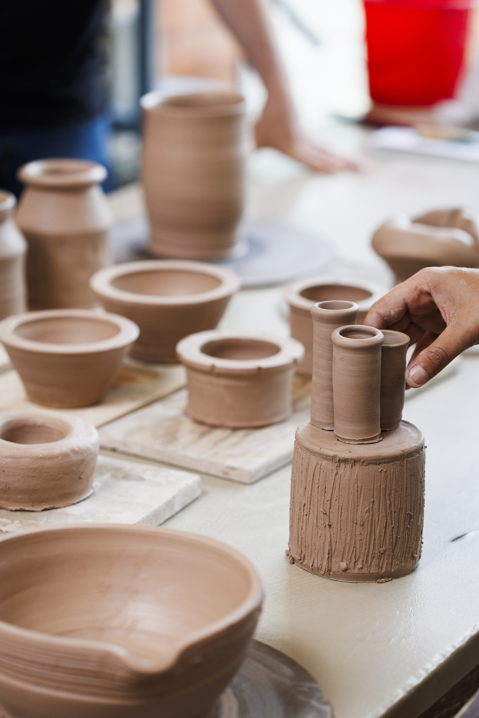 Thrown pots by the entire class are placed on the worktable to review.