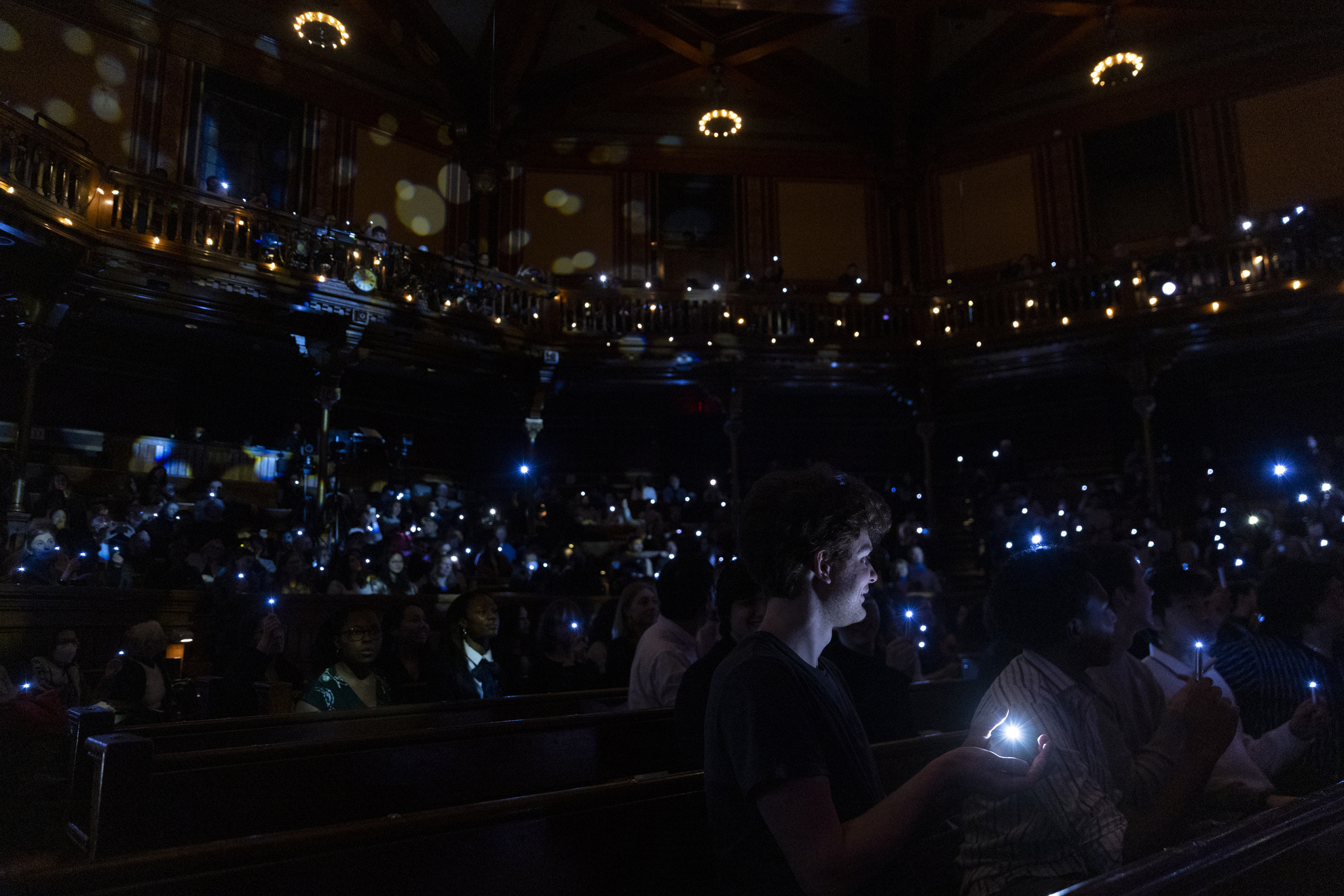 Members of the audience use mini flashlights to show their support for the arts