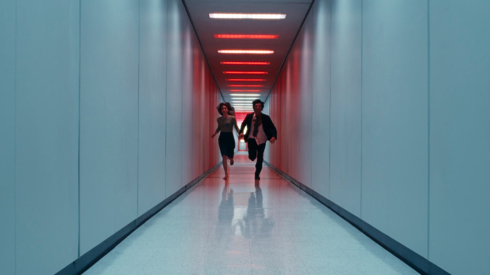 two characters from the show Severance running down a hallway