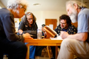 Writers Maria Lisella, Julia Lisella, Josh Kurtz, and Kenny Likis circle a table in Harvard's Woodberry Poetry Room.
