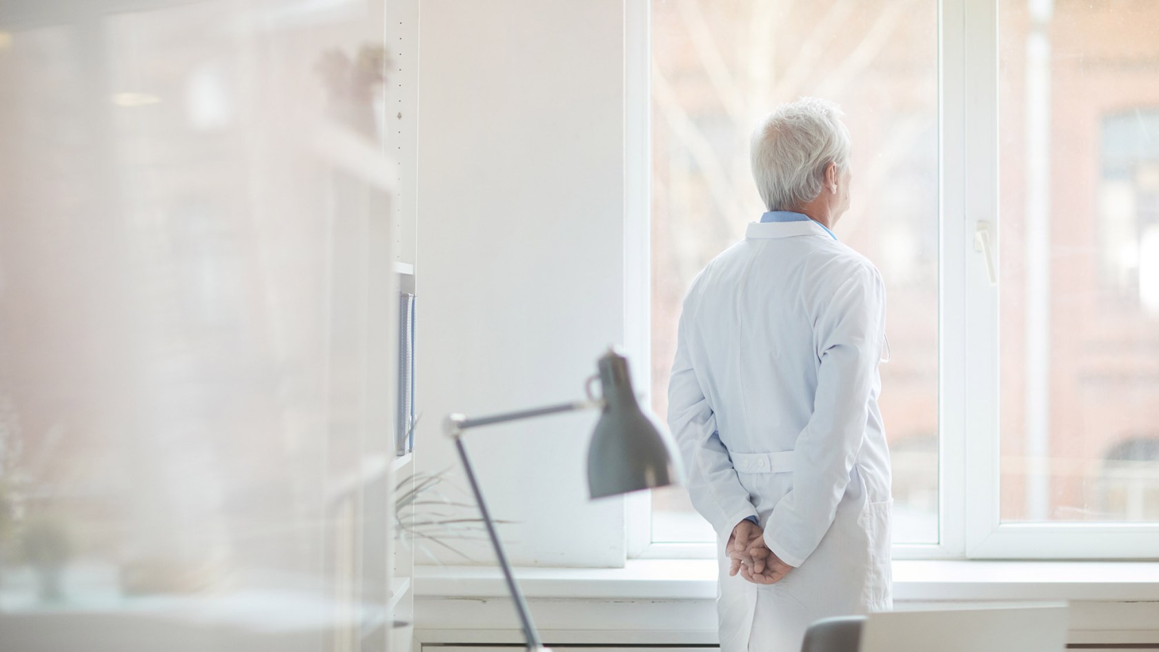Older doctor looking out of a window.