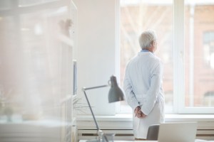 Older doctor looking out of a window.