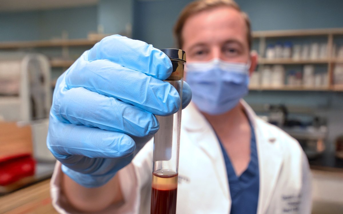 Daniel Faden holding up a vial of blood in his lab at Mass Eye and Ear.