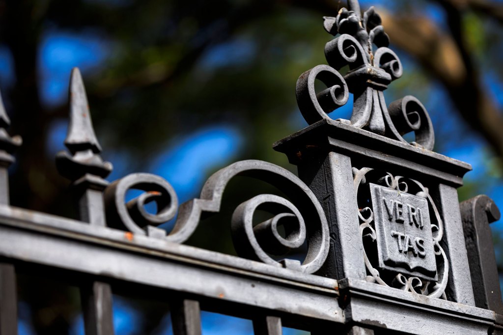 An ornate gate features a veritas shield alongside Harvard Yard.