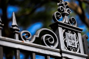 An ornate gate features a veritas shield alongside Harvard Yard.
