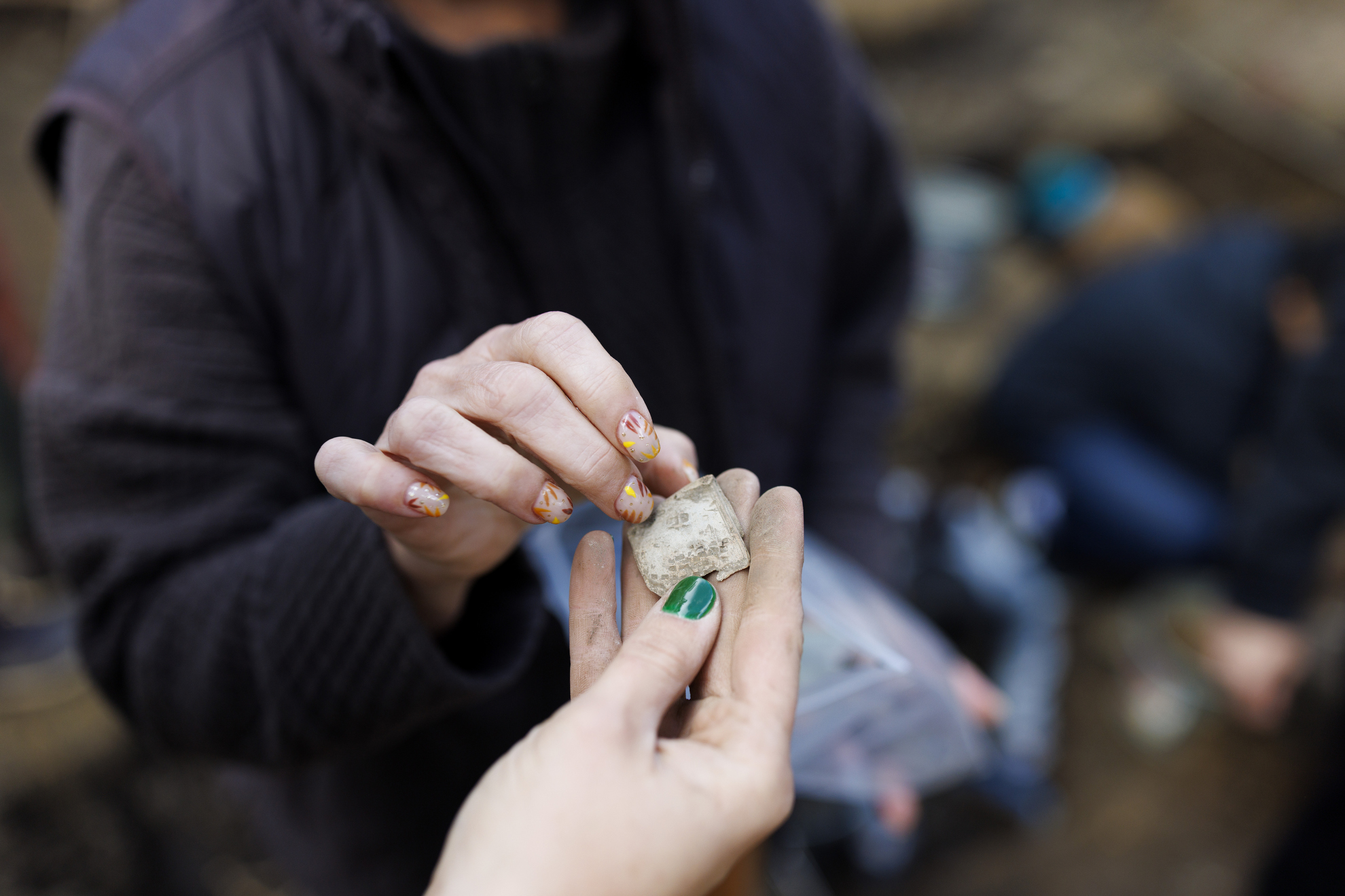 Diana Loren and a student examine an artifact, possibly from a clasp or cover of a book.