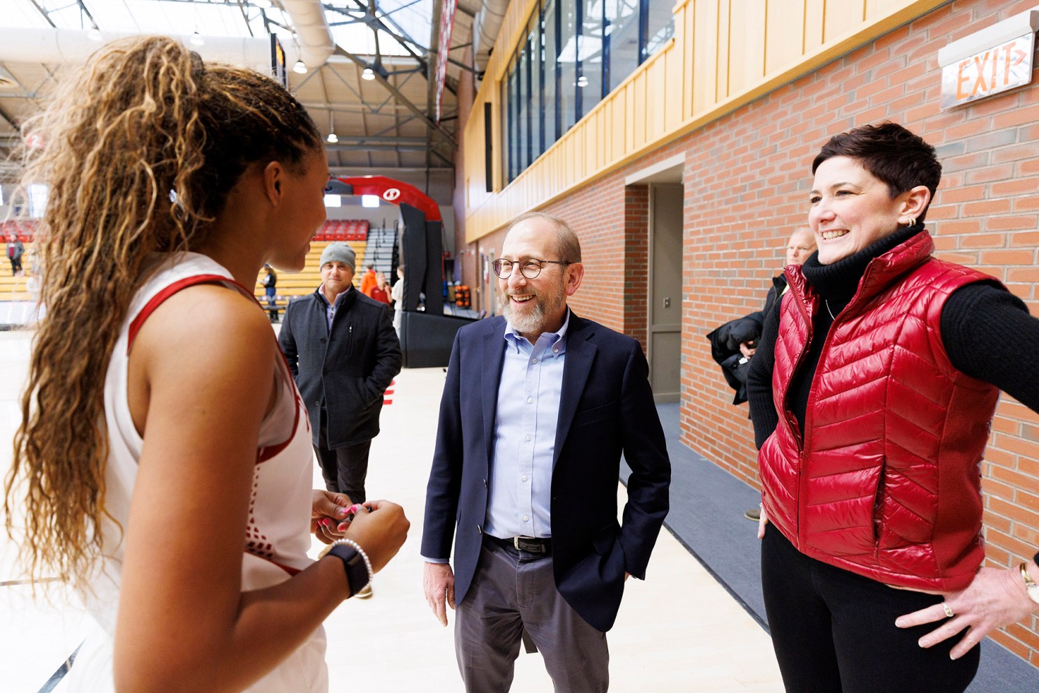 Harvard President Alan Garber talks to women's basketball player Aubrey Shaw and Athletics director Erin McDermott.