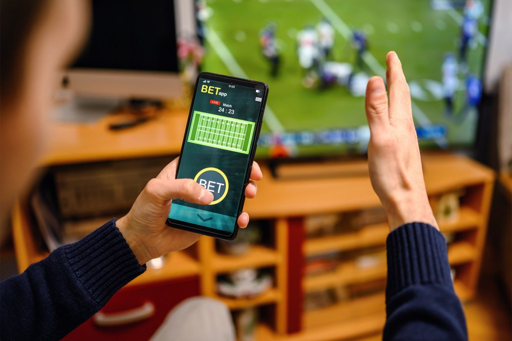 Man using betting app on his smartphone.