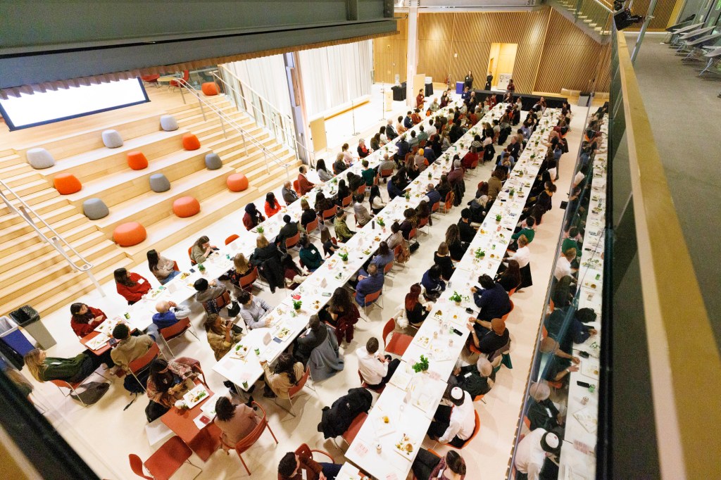 People of different faiths seated at long tables to share a meal in the campus center.