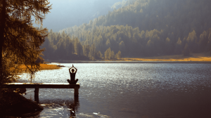 person meditating at lake